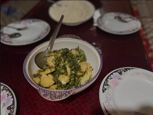 A bowl of greens and potato from our kitchen, served with rice